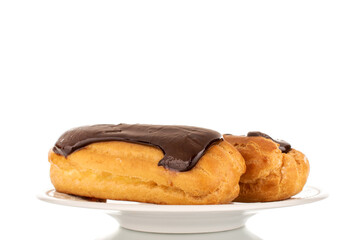 Two sweet chocolate eclairs on a white ceramic plate, macro, isolated on a white background.