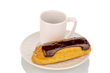 One sweet chocolate eclair with white plate and cup on slate stone, macro, isolated on white...