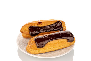Two sweet chocolate eclairs on a white ceramic plate, macro, isolated on a white background.