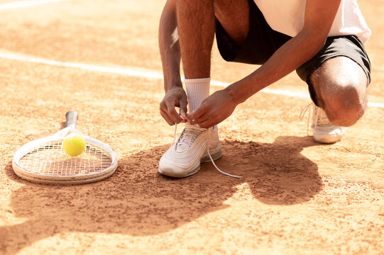 Man in sports shorts tying shoe-strings on his sneakers