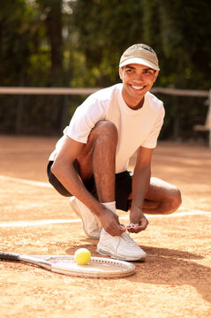 Man in sports shorts tying shoe-strings on his sneakers