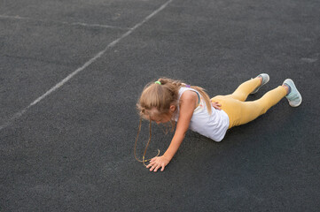 Caucasian girl doing physical exercise on the sports ground outdoors. 