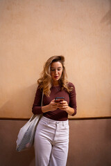 Naklejka premium Woman smiling happy talking on the smartphone with white bag and laptop inside.Walk at the city