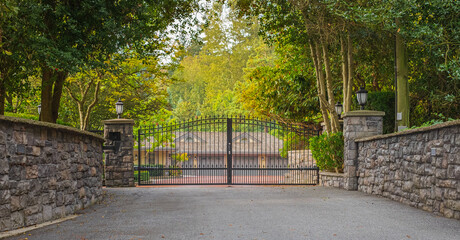 Iron front gate of a luxury home. Wrought iron gate and brick pillar. Nobody, street photo - obrazy, fototapety, plakaty