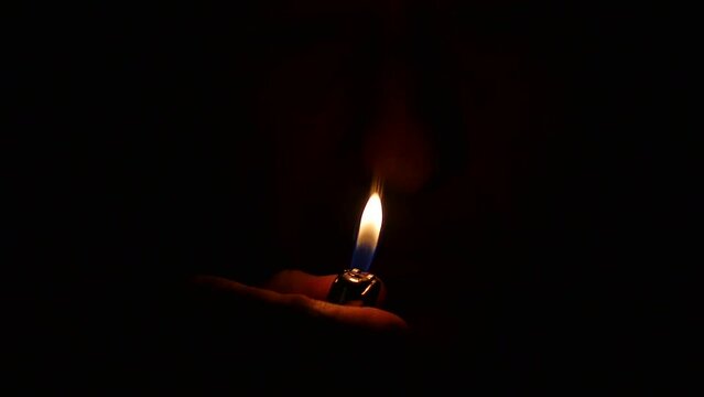Man lights up a lighter in the darkness. Close up Slow Motion. Lighting fire with a lighter in dark. Macro Video
