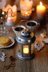 Two types of cookies, cups pf tea or coffee, various Christmas decorations and lit candles. Cozy Christmas atmosphere at home. Selective focus.