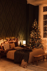 Dark bedroom with Christmas decorations. Large bed and Christmas tree