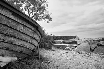 Grayscale of an old wooden boat on a cloudy day