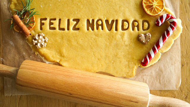 Making cookie words FELIZ NAVIDAD in Spanish language (Merry Christmas in English). Merry Christmas text cutted on shortcrust dough, baking Christmas cookies.  - Powered by Adobe