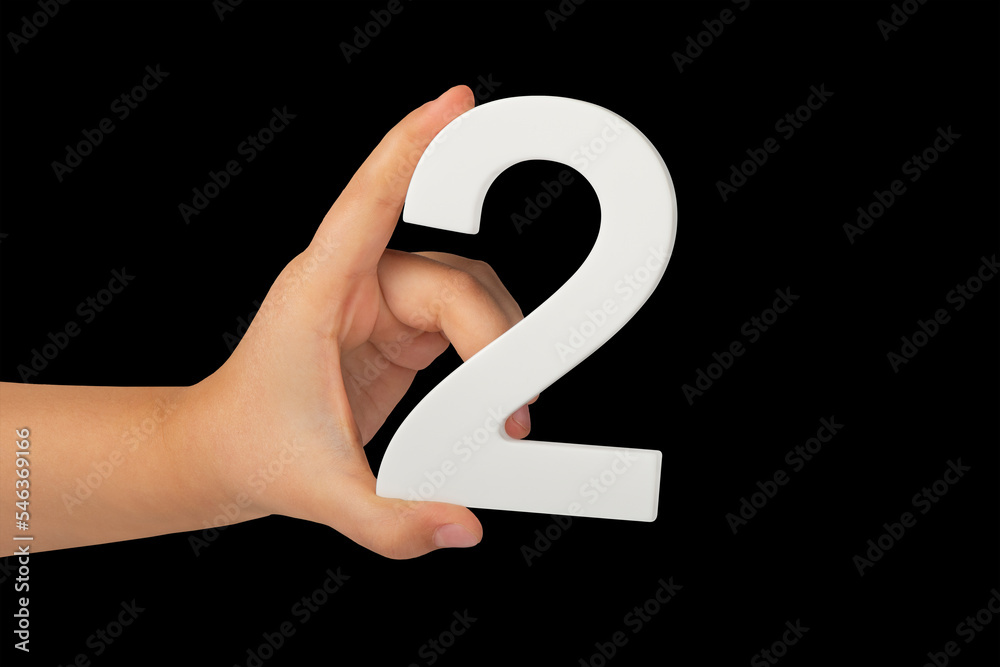 Poster close-up hand holding a white number 2 on a black background. number two isolate on black background