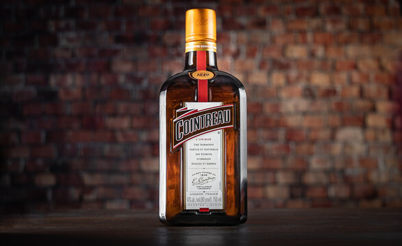 LACEY, WA USA – NOVEMBER 13: An unopened bottle of Cointreau liqueur sits on a wooden table with a brick wall in the background, on November 13, 2022 in Lacey, Washington.