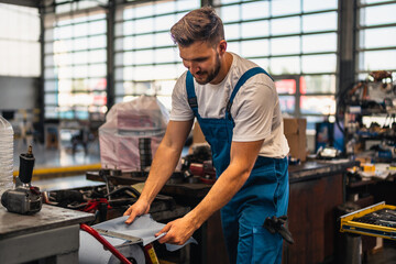 Car service, repair, maintenance and people concept - auto mechanic man or smith cleaning his hands with wipe at workshop