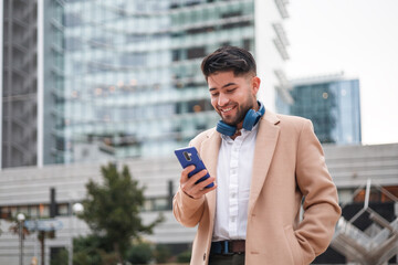 Happy young hispanic man using smartphone and smiling