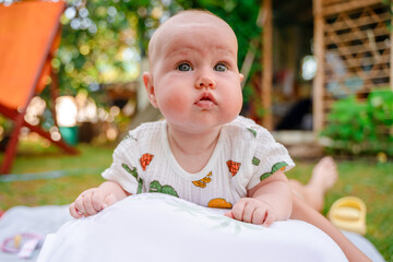 Close-up portrait of a cute Caucasian newborn baby. Charming funny baby looking into the camera. An authentic childhood and a candid lifestyle moment.