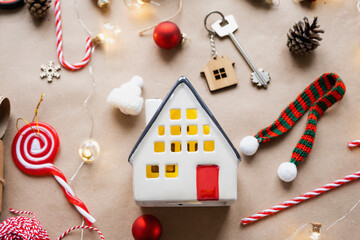Key to the house with a keychain on a cozy home with a Christmas decor layout. A gift for New Year, Christmas. Building, design, project, moving to new house, mortgage, rent and purchase real estate