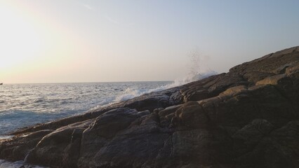 夕日に照らされる岩場に打ち付ける波