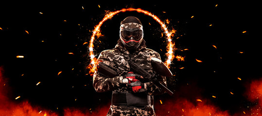 Paintball player man. Lasertag game. armed masked paint ball soldier on fire background....