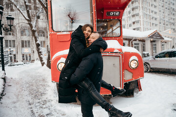 Happy girl hugs her beloved boyfriend and smiles sweetly on the snow city