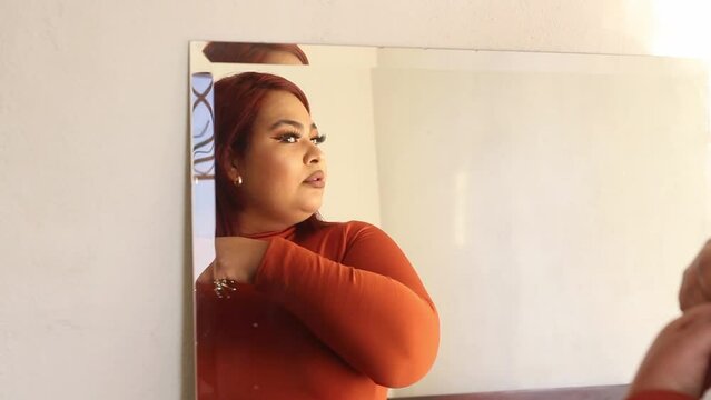 Hispanic plus size woman combing her hair in front of a mirror. mexican chubby