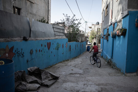 A child is bicycling on a street in a refugee camp in Bethlehem