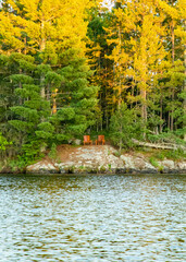 Fototapeta na wymiar Adirondack chairs on the shore of a lake