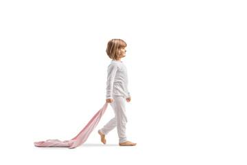 Full length profile shot of a little girl in pajamas walking and holding a ping blanket