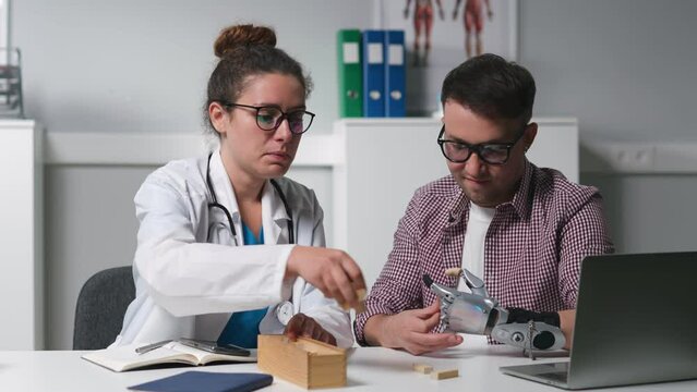 Doctor give small wooden blocks to patient with bionic arm prosthesis at therapy session