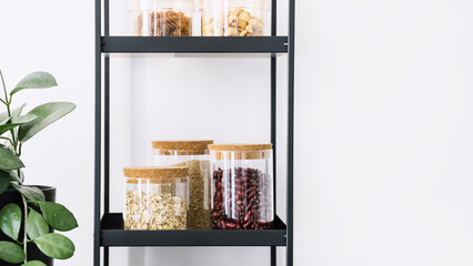 cereals, pasta and beans in glass jars with lid on shelf in kitchen