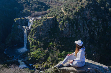 Una chica joven en plena naturaleza viendo una cascada