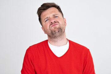 Fototapeta premium Gloomy caucasian man frowns face, looking upwards, pouting lips, being tired.