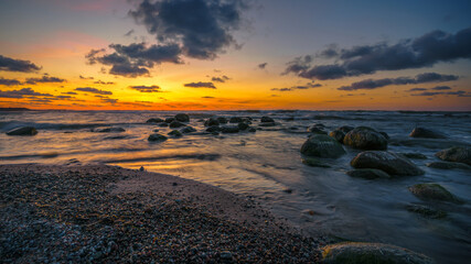 Fototapeta na wymiar Wonderful orange sunset on the rocky coast of the sea