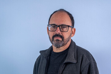 Obraz premium Portrait of 60 years old bearded man on blue background with hat and glasses