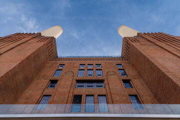 Low angle view at chimneys and brick facade of iconic London landmark Battersea Power Station and surrounding area.