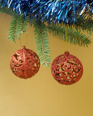 two round red Christmas toys hanging on the green branches of the Christmas tree on a brown background.  New Year .  copy space