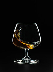 A splash of cognac in a glass on a black background