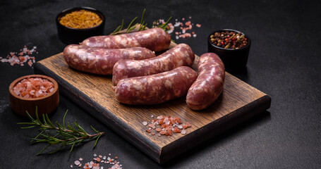 Raw pork sausages grill with spices and herbs on a dark concrete table