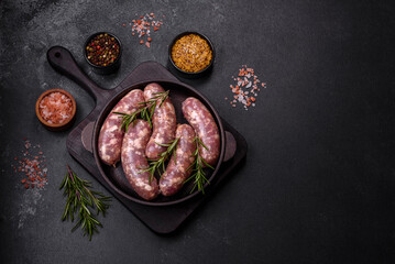 Raw pork sausages grill with spices and herbs on a dark concrete table