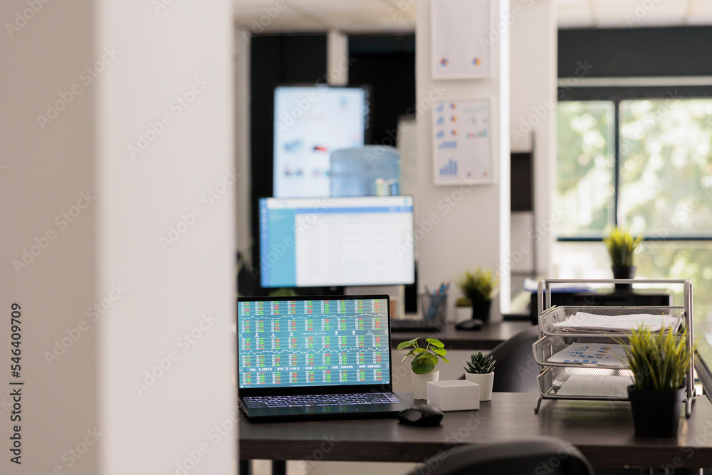Poster inside of empty trading workspace with a portable computer showing the rise and fall of the stock pr
