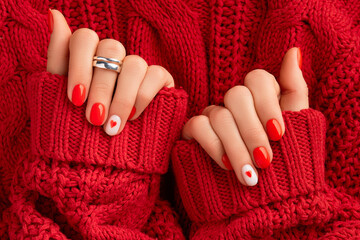 Manicured womans hands in warm wool red sweater. Fashionable valentines day nail design