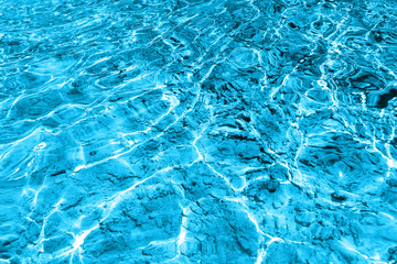 Defocus blurred transparent blue colored clear calm water surface texture with splashes and bubbles. Trendy abstract nature background. Water waves in sunlight with copy space. Blue watercolor shining