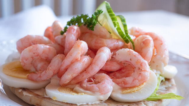 Close up of peeled fresh shrimps on white bread, making a delicious Swedish shrimp sandwich (r&auml;kmacka).
Seafood and food preparation concept.