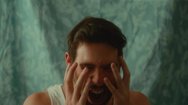 Young Caucasian male yelling and closing his face in front of the camera