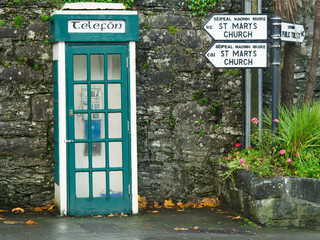 Fototapeta na wymiar Old vintage phone booth with sign telefon in Cong town, Ireland. Green and white exterior color.