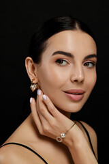Young woman with elegant pearl jewelry on black background