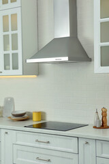 Fototapeta na wymiar Elegant kitchen interior with modern range hood over cooktop and stylish furniture