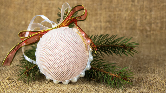 New Year's toys with bows and a Christmas tree branch on a burlap background. Christmas background decorations. Festive New Year's background from round toys