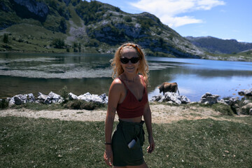 blonde caucasian girl with braces on her teeth looking at camera smiling from the lake, covadonga asturias, spain