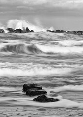 Gray scale long exposure shot of waves at a beach with rocks