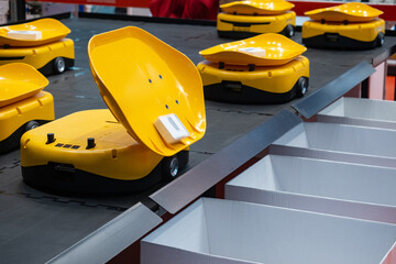 Warehouse sorting robots. Miniature carts for warehouse automation. Yellow sorting robots throw...