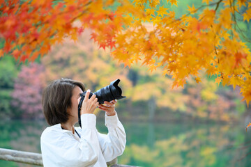 Woman photographing autumn leaves